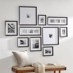 a white wall with many black and white pictures on it, along with a bench