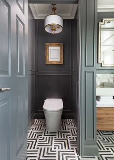 a toilet in a bathroom with gray walls and black and white floor tiles on the floor