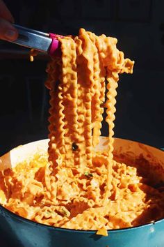 someone is holding up some noodles in a blue bowl