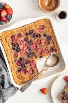 a dessert with strawberries and blueberries in it on a white plate next to two bowls of fruit