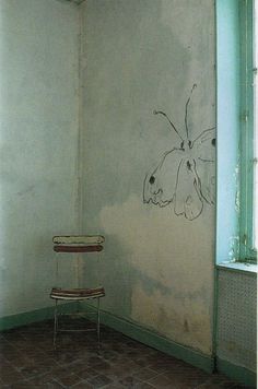 a chair sitting in front of a wall with a butterfly painted on it's side