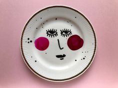 a white plate topped with a face painted on it