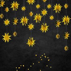 some yellow stars hanging from strings on a black background with gold dots and small white balls