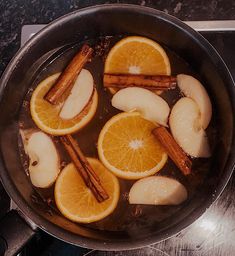 orange slices and cinnamon sticks are cooking in a pan on the stove top with water