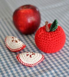 an apple and two pieces of crochet sit on a table