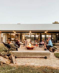 people sitting around a fire pit in front of a house