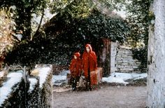 two people in red coats walking through the snow