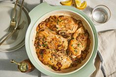 a chicken dish with mushrooms and lemons on the side