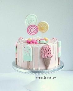 there is a pink cake decorated with candies and lollipops on top