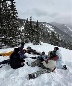 several people sitting in the snow on top of a mountain