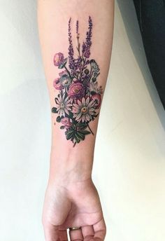 a woman's arm with a flower bouquet tattoo on the left side of her arm