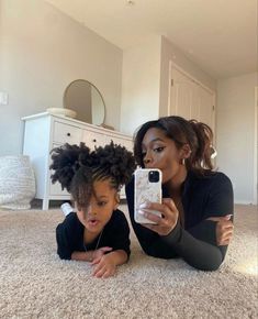 a woman and child laying on the floor taking a selfie with their cell phones