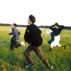 three people running in a field with grass