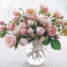 a vase filled with lots of pink flowers on top of a tablecloth covered table