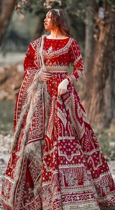 a woman wearing a red and white dress standing in the woods