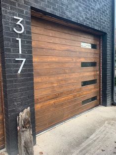 a wooden garage door on the side of a brick building with numbers painted on it