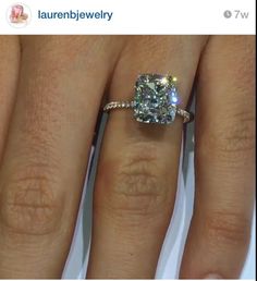 a woman's engagement ring with a cushion cut diamond in the center and two rows of diamonds on each band