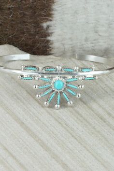 This turquoise and sterling silver bracelet was made by Zuni silversmith Rena Cachina.Size: 5 1/4" (will fit up to a 6 1/4" wrist)Gap: 1"Length: 7/8"Free shipping on all orders! We ship with USPS and always include tracking. All orders ship within a day of payment.Returns are accepted up to 30 days after you receive your order. Just send us a message. Our shop offers cash back or store credit. The item must be returned in new condition. Turquoise Sterling Silver Bracelet, Artisan Turquoise Sterling Silver Bracelet, Adjustable Turquoise Sterling Silver Bracelet In Southwestern Style, Adjustable Southwestern Sterling Silver Bracelet With Turquoise, Adjustable Southwestern Turquoise Sterling Silver Bracelet, Southwestern Sterling Silver Bracelet With Turquoise Inlay, Traditional Turquoise Sterling Silver Cuff Bracelet, Southwestern Turquoise Inlay Sterling Silver Bracelet, Unique Turquoise Nickel-free Bracelets