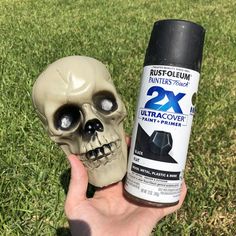 a hand holding a spray bottle next to a fake skull