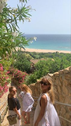 two women and a child are walking up stairs near the ocean on a sunny day