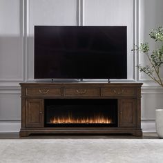 a flat screen tv sitting on top of a wooden entertainment center next to a fire place