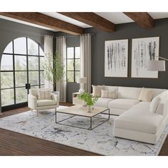 a living room filled with white furniture and large window covered in artfully framed pictures