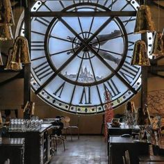 a large clock mounted to the side of a wall in a room filled with tables and chairs