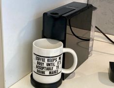 a coffee mug sitting on top of a counter next to a computer mouse and keyboard