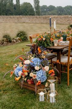 an outdoor table set up with flowers and candles for a wedding reception in the grass