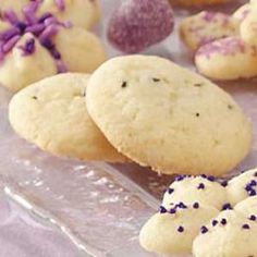 some cookies and other pastries are on a plate with purple sprinkles