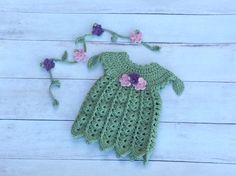 a crocheted green dress with pink flowers on the side and purple flowers on the back