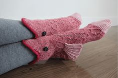 two knitted mittens sitting on top of each other in front of a wooden floor