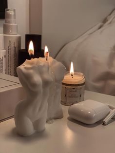 two candles sitting on top of a white table next to a mouse and some books