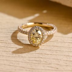 a yellow diamond ring sitting on top of a wooden table