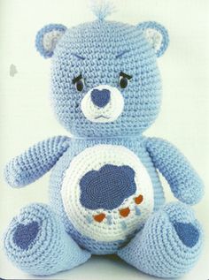 a crocheted blue teddy bear sitting up against a white background