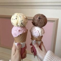 two people holding ice cream cones with chocolate chip cookies and oreo cookies on top