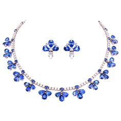 The blue sapphire and diamond necklace consists of 13 articulated flowers set with drop shape faceted sapphires of brilliant color and crystalline texture. The flower designs are slightly graduated in symmetrical fashion and are attached to a riviera of round diamonds interleaved with round cut blue sapphires. The total carat weight of blue sapphire is 72.40 carats, and the total weight of round diamonds is 5.95 carats. The earrings features a leaf like design with pear shape faceted Ceylon sapp Diamond Flower Necklace, Blue Diamond Necklace, Sapphire Diamond Necklace, Diamond Chain Necklace, Diamond Pendants Designs, Blue Sapphire Necklace, Diamond Tennis Necklace, Diamond Necklace Set, Ceylon Sapphire