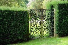 an iron gate in the middle of some bushes