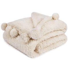 a white blanket with pom - poms on the top and bottom is folded up