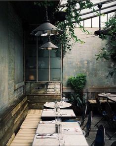 an empty restaurant with tables and chairs in front of the window, surrounded by greenery