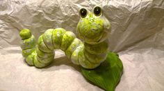 a green and white snake figurine sitting on top of a leaf