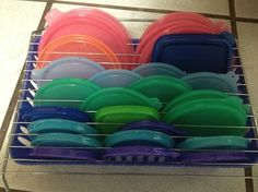 a rack filled with lots of different colored plastic plates and bowls on top of a tiled floor