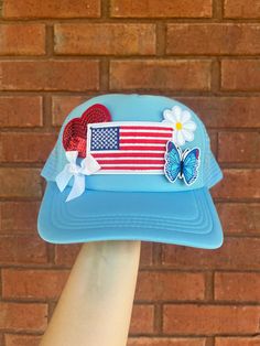 a person's hand holding up a hat with an american flag design on it