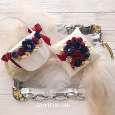 two wedding garters with red, white and blue flowers on them sitting in a silver tray