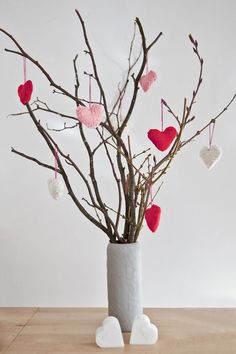 a vase filled with branches and hearts hanging from it