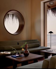 a living room filled with furniture and a large window looking out to the ocean on a sunny day