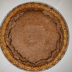 a pie crust in a metal pan on a white counter top with no one around it