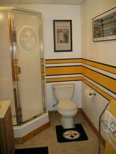 a bathroom with yellow and black stripes on the walls, white toilet and shower stall