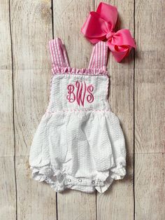 Check out this adorable monogrammed sunsuit! The perfect outfit to keep your little one cool yet stylish in those hot summer months! This sunsuit is available in white seersucker with pink seersucker trim, white seersucker with white trim, or white seersucker with rainbow (multi) trim. Made from 100% cotton. It is fully lined, with snaps at the crotch and the shoulder straps tie in a bow. It also has elastic in the leg openings. A large monogram is embroidered directly onto the romper using thre White Ruffle Bubble Romper For Summer, Spring White Bubble Romper For Beach, White Spring Bubble Romper For Beach, Summer White Bubble Romper With Ruffles, White Ruffled Bubble Romper For Summer, Summer White Ruffle Bubble Romper, Summer Gingham Cotton Bubble Romper, White Summer Bubble Romper For Beach, White Fitted Bubble Romper For Playwear