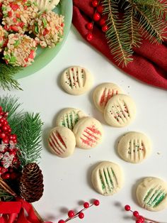 christmas cookies decorated with red, green and white icing on a table next to pine cones